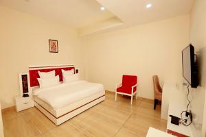 a bedroom with a bed and a red chair at Hotel The Spades in Zirakpur +19 photos