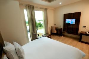 a bedroom with a white bed and a television at Hotel The Spades in Zirakpur