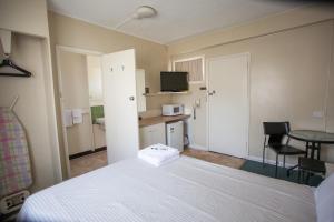 a kitchen with a white refrigerator and a white bed at Corio Bay Motel in Corio
