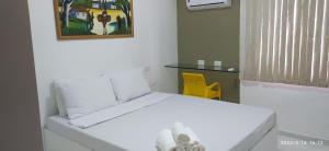 a white bed in a room with a yellow chair at No coração de Boa Viagem in Recife