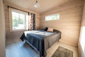1 dormitorio con 1 cama en una cabaña de madera en Villa Kuulas, en Sääskilahti