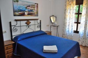 a bedroom with a blue bed with a blue blanket at CASA PEPE Y MARI CON PISCINA in Alora