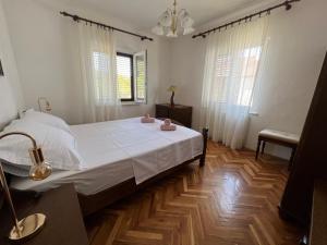 a bedroom with a large bed with white sheets and wooden floors at Villa Slatine apartment in Slatine