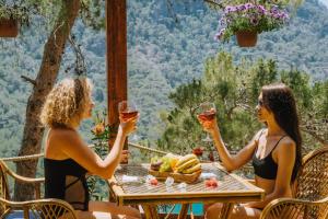 two women sitting at a table with glasses of wine at MANZARA BUNGALOW in Fethiye