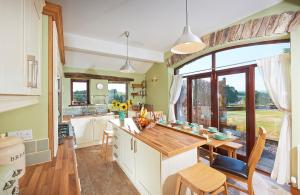 a kitchen with a table and a large window at Canny Brow Barn Garden Rooms in Kendal