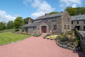 una antigua casa de piedra con un jardín delante de ella en Canny Brow Barn Garden Rooms en Kendal