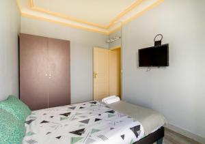 Un dormitorio con una cama y un televisor en la pared. en Au PIED de la GARE aux PORTES de PARIS, en Vitry-sur-Seine