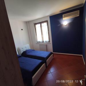 two beds in a room with a blue wall at M & M Pinzi Suite Apartment in Montepulciano Stazione