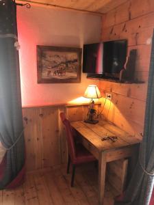 a room with a wooden table with a lamp and a television at Les Loft's de Mika in Briançon