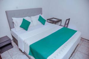 um quarto com uma cama grande e almofadas verdes em Martin Aviator Hotel em Kigali