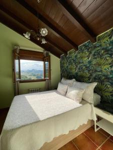 a bedroom with a large white bed with a green wall at El Portiellu in Cabielles