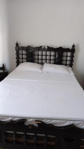 a white bed with a wooden headboard and white pillows at Precioso alojamiento con 6 piscinas en conjunto cerrado in Espinal +20 photos
