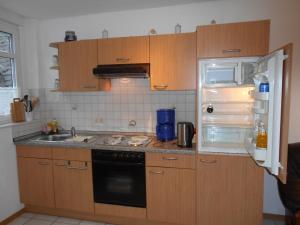 a kitchen with wooden cabinets and an open refrigerator at Wohnung Feuerberg mit Südbalkon in Ediger-Eller