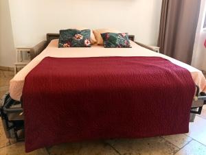 a bed with a red blanket and pillows on it at le Travertin in Avignon