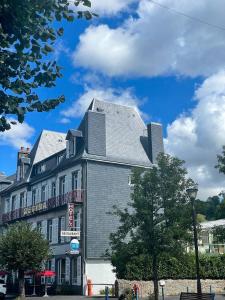 un bâtiment avec un toit gris dans une rue dans l'établissement Logis Regina, à La Bourboule
