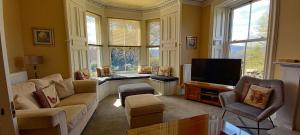 sala de estar con sofá y TV en Kinnaird Country House en Pitlochry