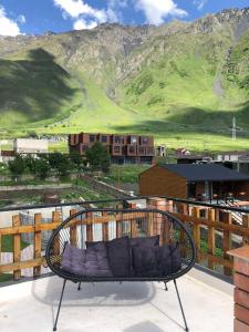 een bank bovenop een balkon met uitzicht op de bergen bij Vache Hotel in Kazbegi