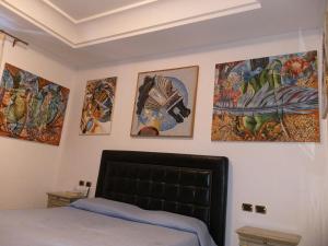 a bedroom with four paintings on the wall at Appartamento Deluxe Centrale, in Gaeta