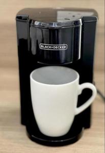 a coffee maker with a white cup on a table at Abeer Story Hotel Suites in Jeddah