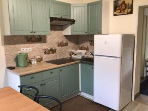 a kitchen with green cabinets and a white refrigerator at Рукавичка in Yaremche