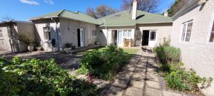 a house with a dog sitting outside of it at AppleBee Guest Cottages in Grahamstown