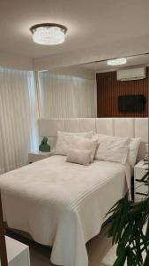 a bedroom with a large white bed with a chandelier at Lindo flat Easy Life in Goiânia