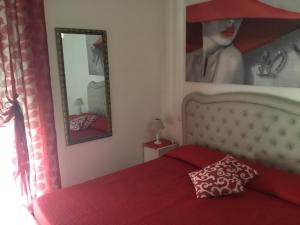 una camera con letto rosso e specchio di da Ysabel a Verona