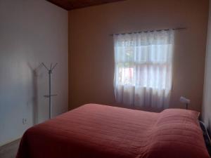 um quarto com uma cama vermelha e uma janela em Sua Casa na Cidade dos Canyons - Cambará do Sul-RS em Cambará