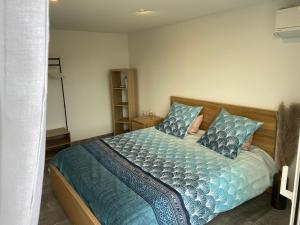 1 dormitorio con 1 cama con sábanas y almohadas azules en Maison Climatisée proche du lac de Freminville, en Tignieu-Jameyzieu