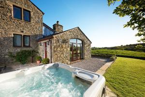 a swimming pool in front of a stone house at Canny Brow Barn Garden Rooms in Kendal