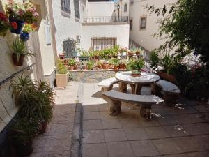 a patio with a table and benches and potted plants at Miguel y Rosa Lúcar in Lúcar