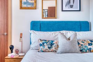 a bed with a blue headboard and pillows at Gorgeous 1-bed city apartment, sleeps 4 in Worcester