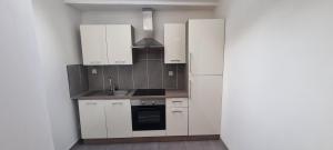 a kitchen with white cabinets and a sink and a refrigerator at Maison de Luxe Centre ville avec 6 lits et Garage in Valenciennes