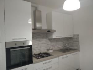cocina con armarios blancos y fogones en appartamento la pineta 10058-LT-0004, en Serra Rocco