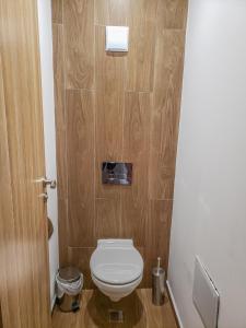 a bathroom with a toilet and a wooden wall at Lovely Borovets Apartment in Borovets