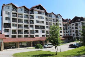 a large apartment building with cars parked in a parking lot at Lovely Borovets Apartment in Borovets