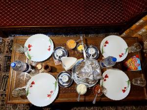 Tashkand Houseboat في سريناغار: طاولة مليئة بالأطباق والأطباق البيضاء والحمراء
