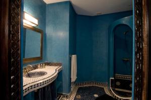 een blauwe badkamer met een wastafel en een spiegel bij RIAD N° 16 in Marrakesh
