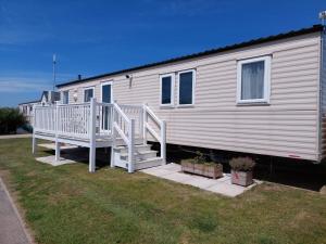 a mobile home with a staircase and a porch at Grouse 54, Scratby - California Cliffs, Parkdean, sleeps 6, pet friendly, bed linen, towels and Wi-Fi included in Scratby