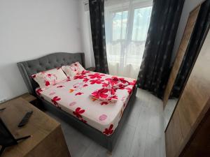 a bedroom with a bed with red flowers on it at R&C Relax Apartment 808 in Dudu