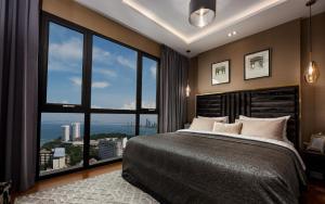 a bedroom with a large bed with a large window at The Elysium Prațumnak Pattaya - By SHG in Pattaya South