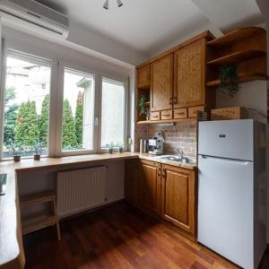 La cuisine est équipée d'un réfrigérateur blanc et de placards en bois. dans l'établissement Bartók Béla Apartman, à Győr