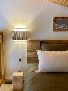 Un dormitorio con una cama con una lámpara al lado en Appartement ensoleillé aux Tines, vue Massif en Chamonix-Mont-Blanc