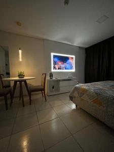 a bedroom with a bed and a table and a tv at Suíte luxo com tela de cinema no América Towers Studio Residence in Salvador