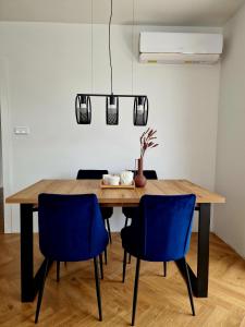 a dining room with a wooden table and blue chairs at Piękny apartament położony w środku lasu in Dywity
