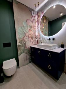 a bathroom with a sink and a flower mural at Piękny apartament położony w środku lasu in Dywity