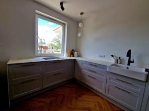 a kitchen with a sink and a window at Piękny apartament położony w środku lasu in Dywity
