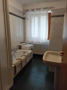 a bathroom with a tub and a toilet and a sink at Appartamento Emma in Molveno