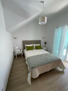 a white bedroom with a large bed with green pillows at Alojamento S. Gabriel 1 in Monchique