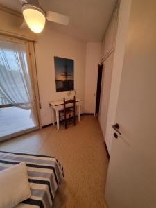 um quarto com uma cama, uma secretária e uma janela em Condomino Giuditta em Porto Santa Margherita di Caorle